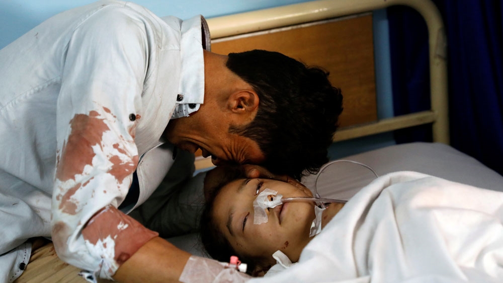 A man cries beside a wounded girl at a hospital after the attack in Kabul [Mohammad Ismail/Reuters]