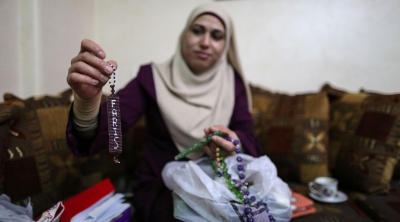 Using beads provided by the Red Crescent and synthetic thread from the potato and onion sacks, Abu Sbaih made this for her son, Faris [Showkat Shafi/Al Jazeera] 