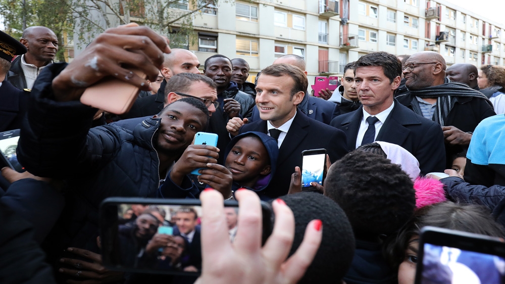 Macron poses as he meets residents of the Cite du Chene Pointu in Clichy-sous-Bois, northern Paris, France, as part of a visit focused on the theme of urban planning [File: Ludovic Marin/EPA]