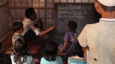 Mohammed Abdullah teaches children at a temporary learning centre at Kutupalong camp [Siddharth Adelkar/Al Jazeera]