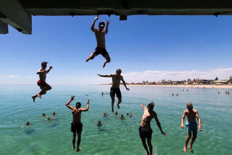 Jetty Jumpers escape the heat by cooling off at Henley Beach, west of Adelaide, Australia.