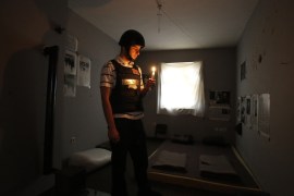 In this Nov. 12, 2016 photo, Bosnian Arian Kurbasic, the owner of the War Hostel in Sarajevo stands with a lit candle in his hand in one of the sparsely furnished hostel rooms...