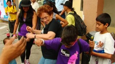 Nelsa Curbelo, peace activist and founder of gang youth rehabilitation foundation Ser Paz, dances with school children [Al Jazeera]