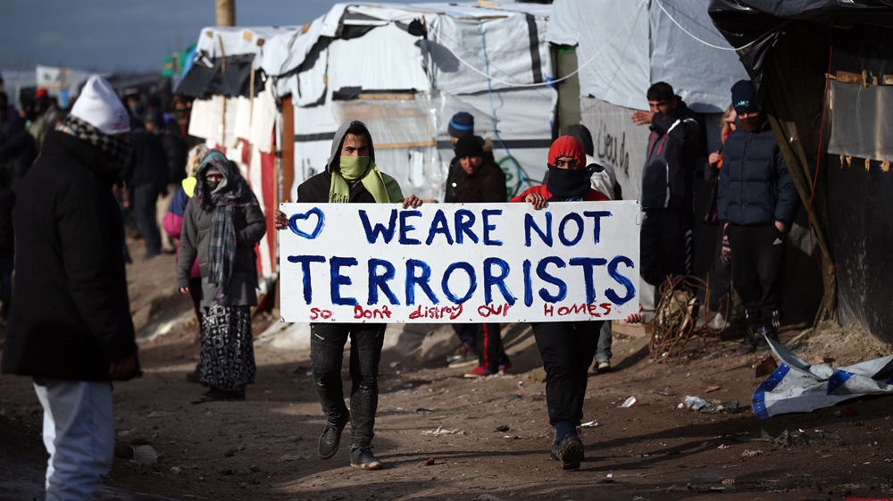 Migrants carry a placard as part of the so-called jungle camp is cleared in February 2016 in Calais, France [Carl Court/Getty Images]