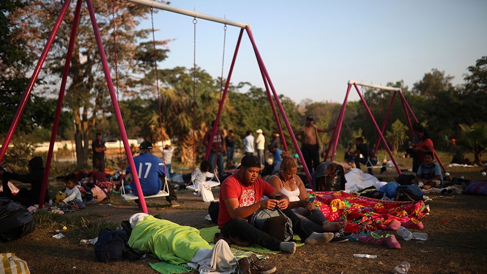 A couple checks their cell phones as Central Americans travelling with the caravan begin their day at a sports club in Matias Romero, Oaxaca State, Mexico [Felix Marquez/AP Photo]