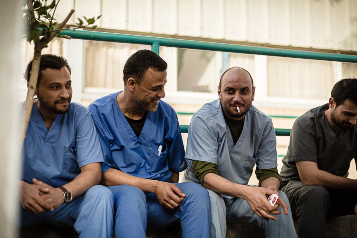 Doctors and nurses taking a smoke break outside the hospital after a long stressful day. Location: European Gaza Hospital. Photographer: Alyona Synenko/ICRC