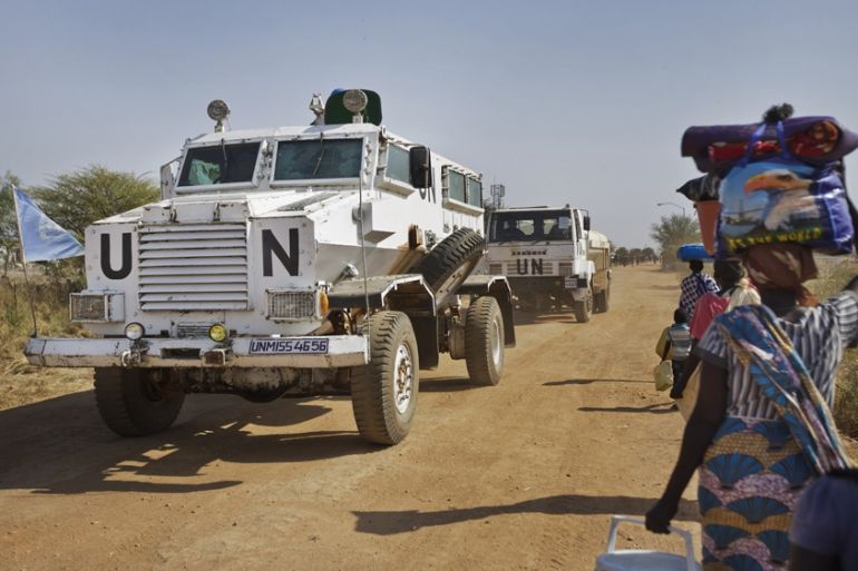 A United Nations armored vehicle travelling in convoy with a truck passes displaced people walking towards the U.N. camp where they have sought shelter in Malakal, South Sudan [File/Ben Curtis/AP]