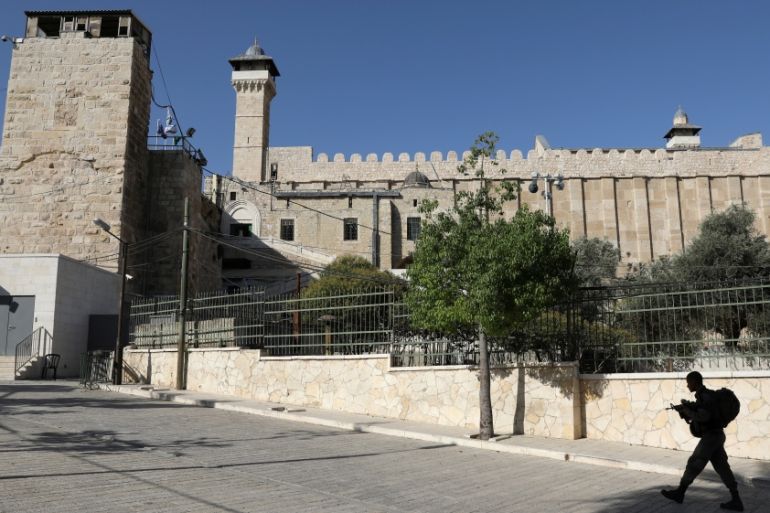 An Israeli soldier walks past Ibrahimi Mosque, which Jews call the Jewish Tomb of the Patriarchs, in the West Bank city of Hebron