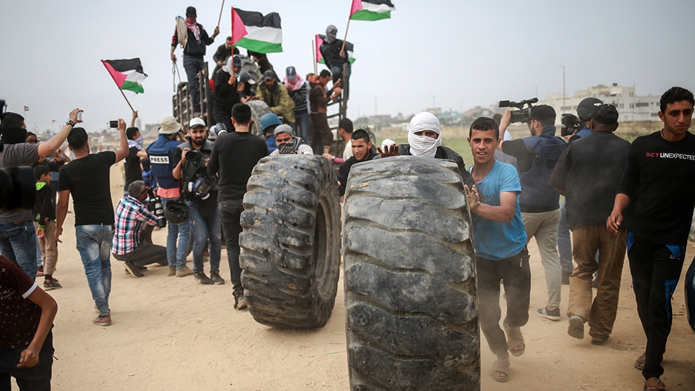 Palestinian youth move and burn tyres near the eastern border of Gaza city [Hosam Salem/Al Jazeera]