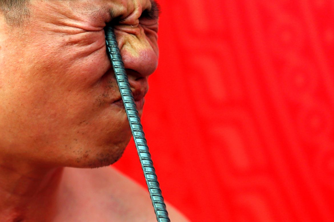 Ngo Chien Thuat, a traditional health worker, bends a metal pole by pressing it into his eye as he performs during a showcase of the traditional Thien Mon Dao kung fu at Du Xa Thuong village in Vietna