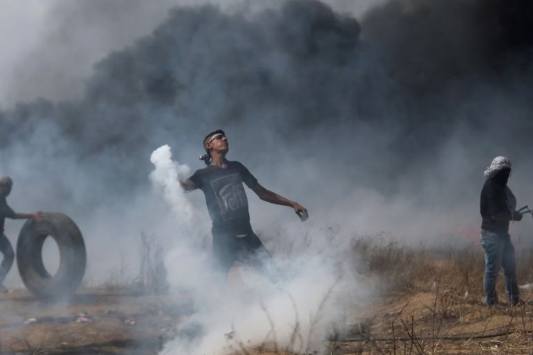Demonstrator hurls back a tear gas canister fired by Israeli troops, at the Israel-Gaza border in the southe