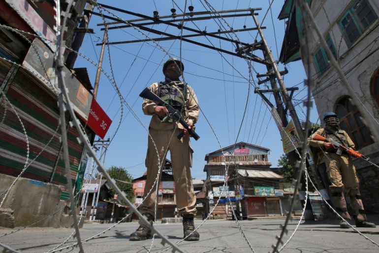Indian policemen stand guard behind concertina wire during a strike called by separatists