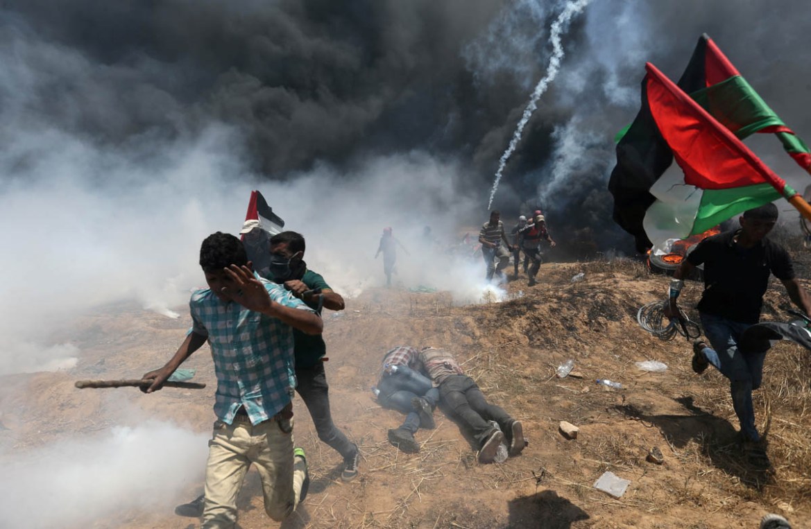 Palestinian demonstrators run for cover during a protest against U.S. embassy move to Jerusalem and ahead of the 70th anniversary of Nakba, at the Israel-Gaza border in the southern Gaza Strip May 14,