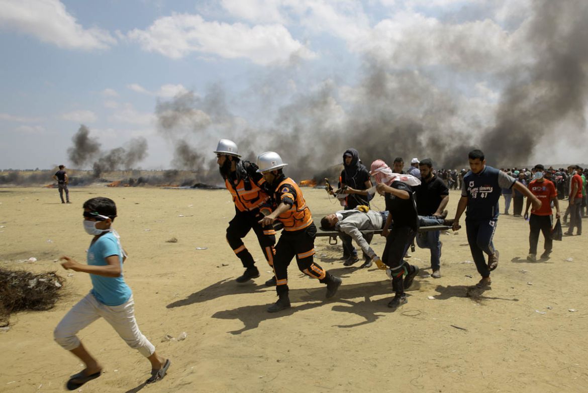 Palestinian medics and protesters evacuate a wounded youth during a protest at the Gaza Strip''s border with Israel, east of Khan Younis, Gaza Strip, Monday, May 14, 2018. Thousands of Palestinians are