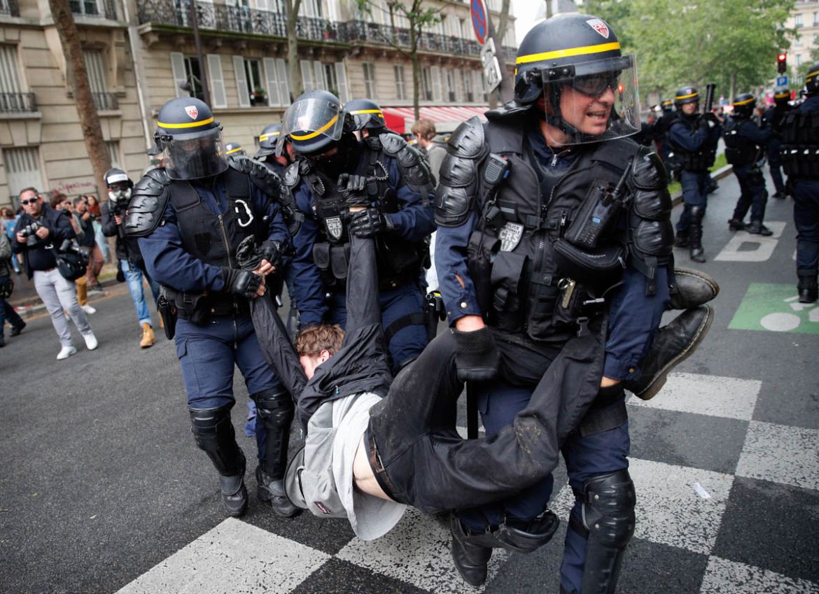 Riot police officers detain a demonstrator during a demonstration in Paris, Tuesday, May 22, 2018. French public services workers have gone on strike as part of their protest a government plan to cut