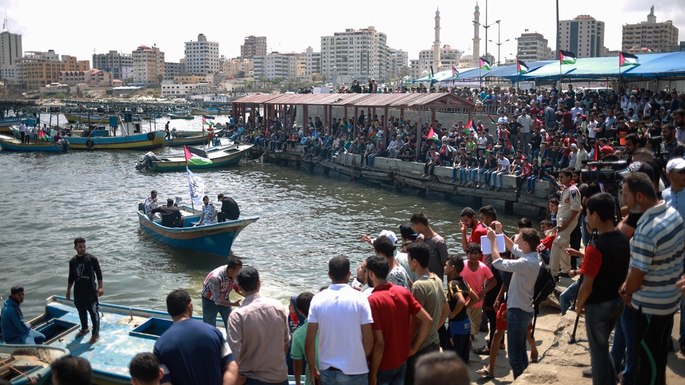 Civilians wait to board boats in support of the main vessel heading for Cyprus [Hosam Salem/Al Jazeera]