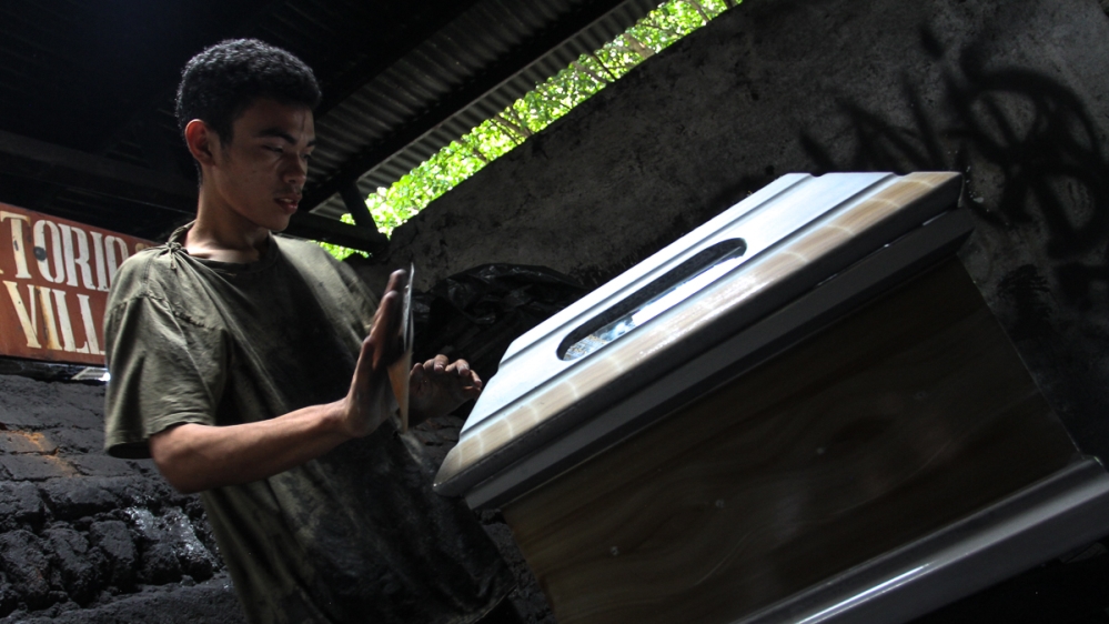 Salvador gives finishing touches to a coffin [Ali Rae/Al Jazeera]