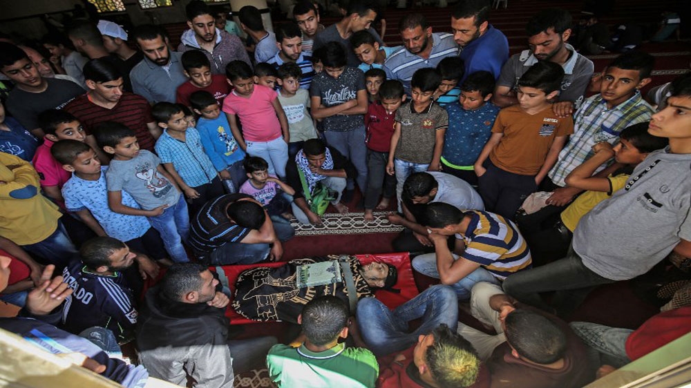 Palestinian mourners gather around the body of a man who was killed by Israeli forces on the Gaza border [AFP].