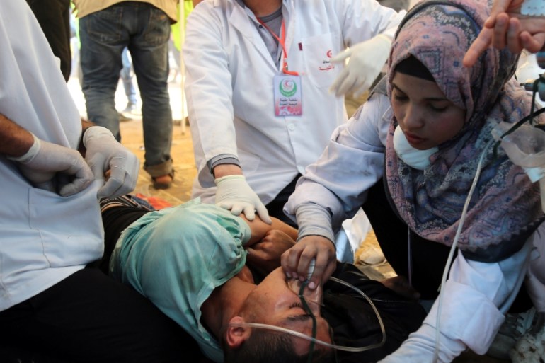 Shorouq Abu Musameh, who volunteers with other paramedics, tends to a Palestinian who inhaled tear gas fired by Israeli troops during a protest, at the Israel-Gaza border, in the southern Gaza Strip