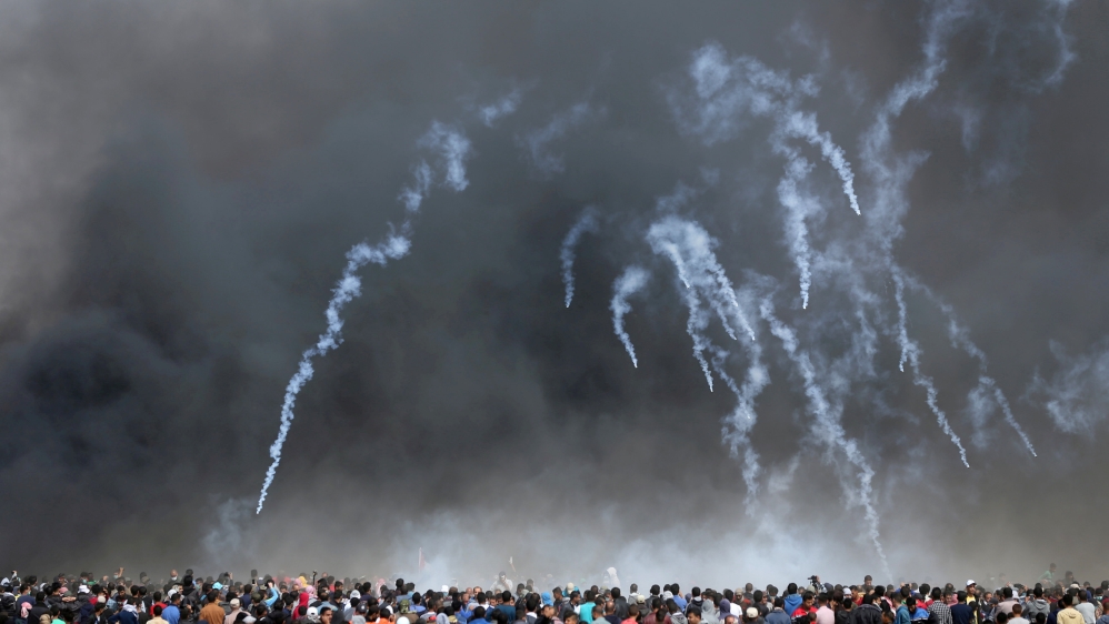 Tear gas canisters are fired by Israeli troops at Palestinian demonstrators at the Israel-Gaza border [Ibraheem Abu Mustafa/ Reuters]