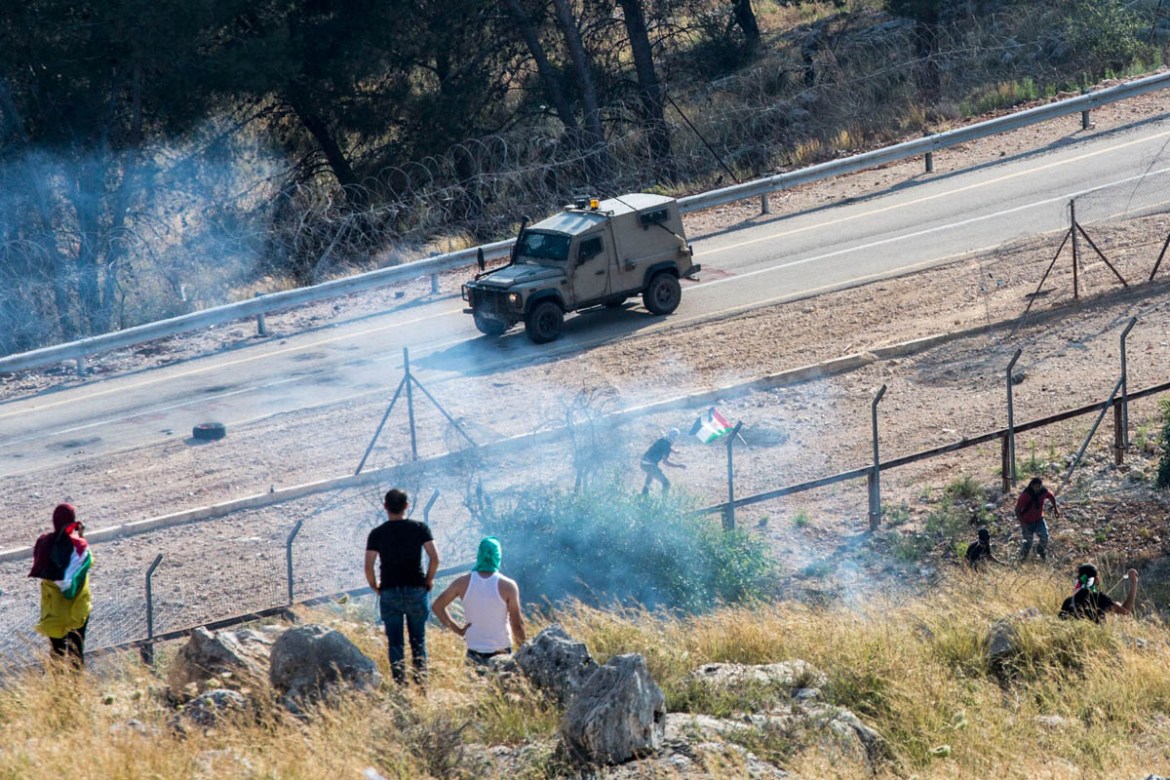 A Palestinian youth throws stones at an Israeli jeep after he broke the Israeli barrier here constituted by a series of barwire and electric fences, Budrus.
