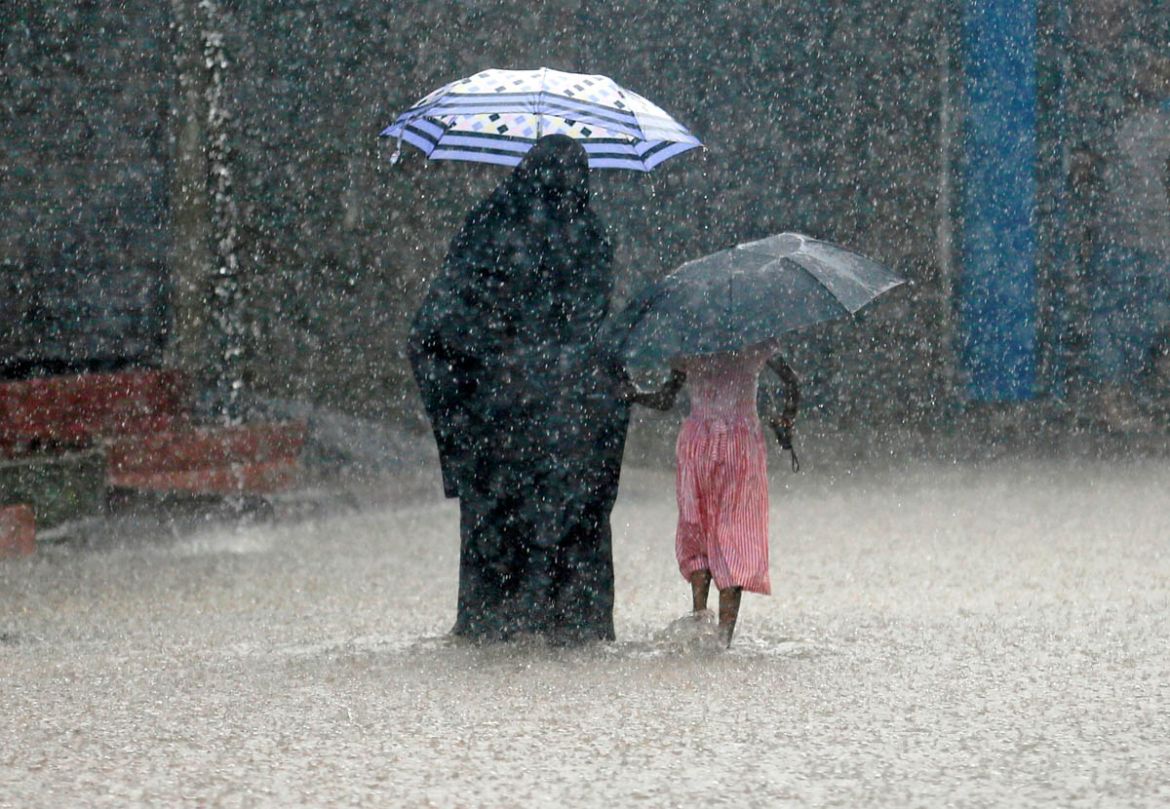 A woman walks with a girl along a flooded road in the heavy rains in Malwana, Sri Lanka May 23, 2018. REUTERS/Dinuka Liyanawatte