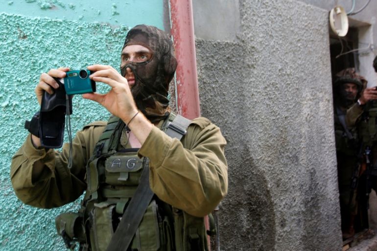 Israeli army soldier films during clashes with Palestinians following a searching raid in the West Bank Al-Fawwar refugee camp, south of Hebron