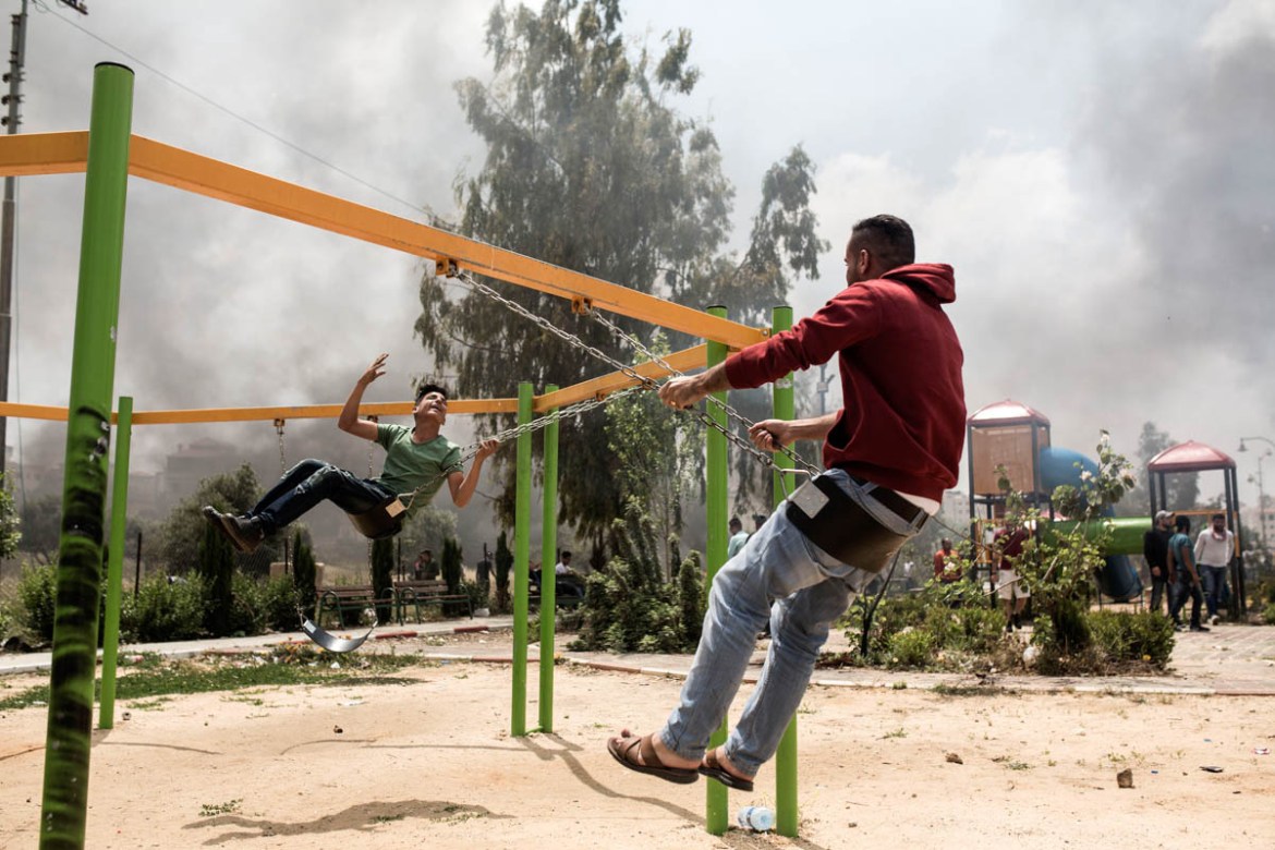 Palestinian youth enjoy swinging during a moment of quiet amidts the clashes.