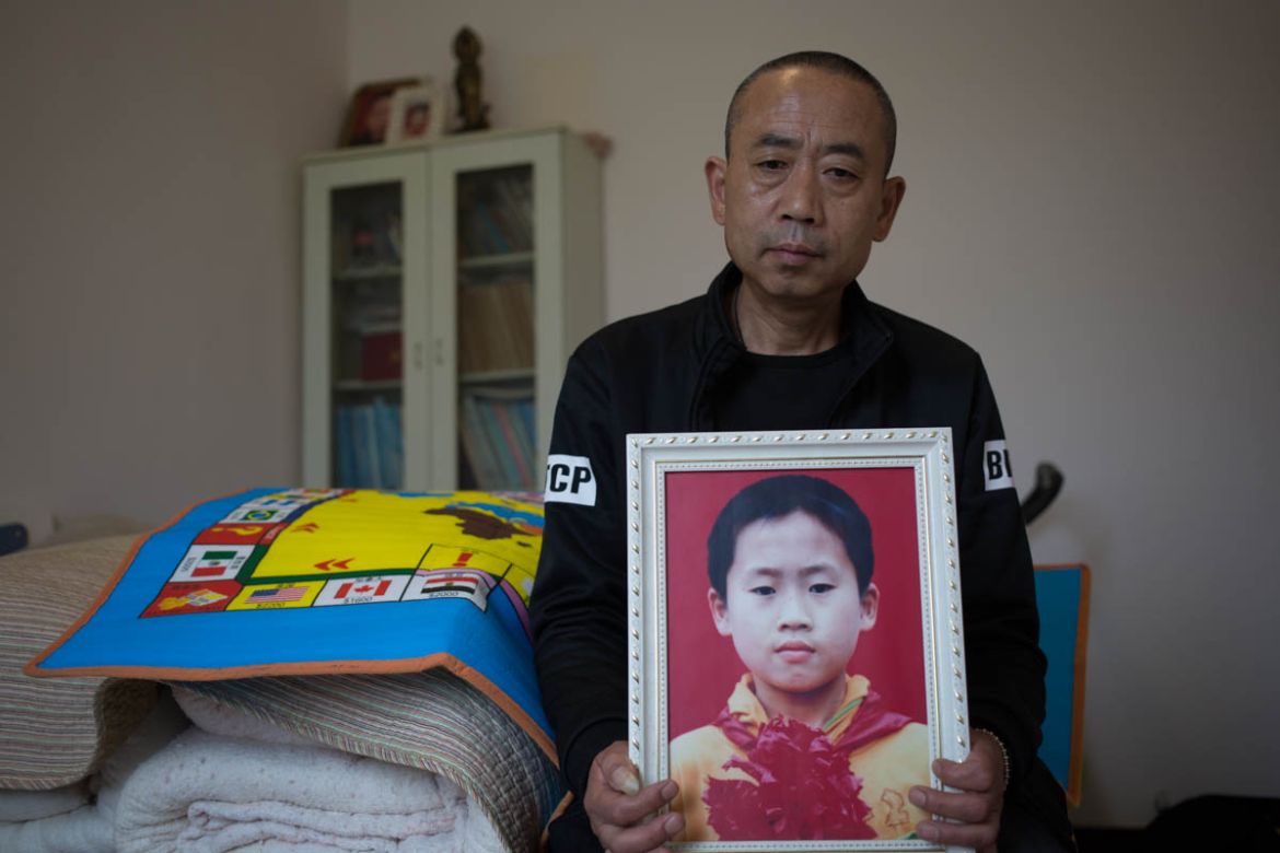 Zhao holds a framed portrait of his son Zhao Yi. Zhao said he finds it impossible to forget his son and often times he stays alone in his room, holding the portrait of his son.