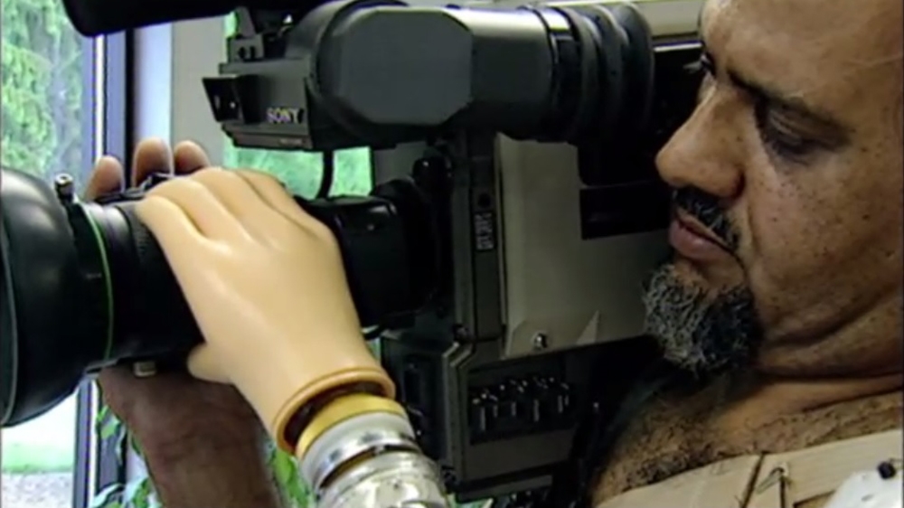 
His prosthetic arm allowed Mo to operate his lens and charge his camera from the battery [Screengrab/Al Jazeera]
