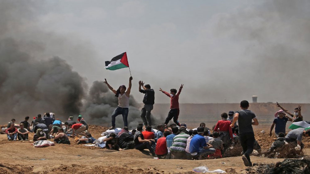 Palestinians wave their national flag as they demonstrate near the border between Israel and the Gaza Strip, east of Jabalia [AFP]