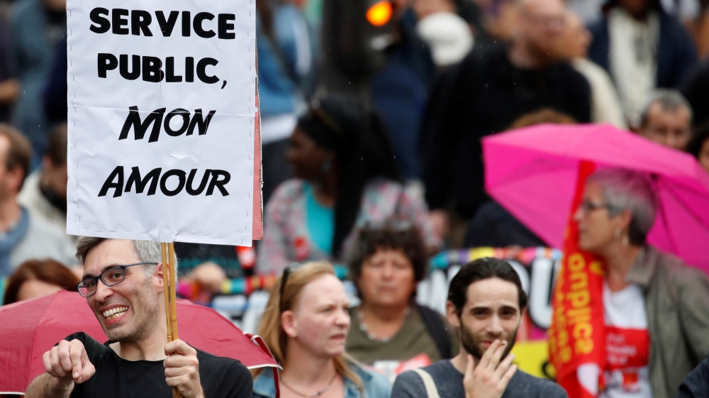 A demonstrator carries a placard that reads, 'Public service, My Love' [Christian Hartmann/Reuters]
