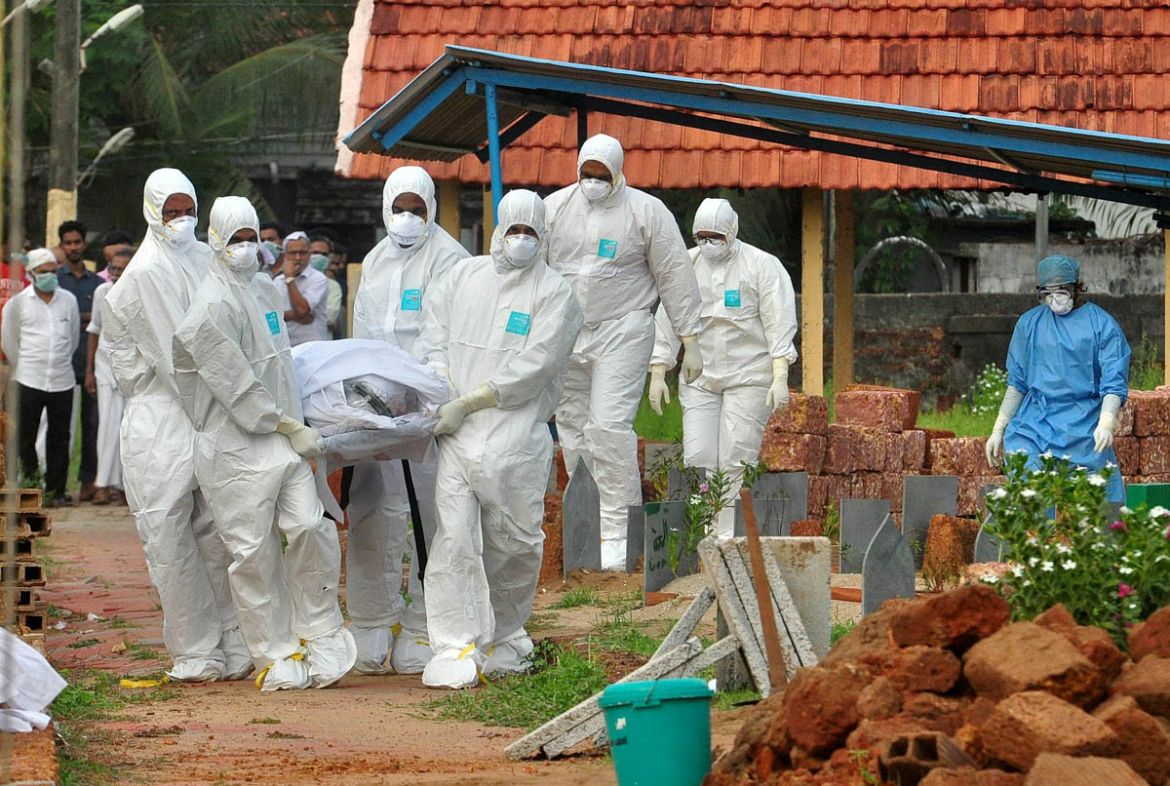 Doctors and relatives wearing protective gear carry the body of a victim, who lost his battle against the brain-damaging Nipah virus, during his funeral at a burial ground in Kozhikode, in the souther