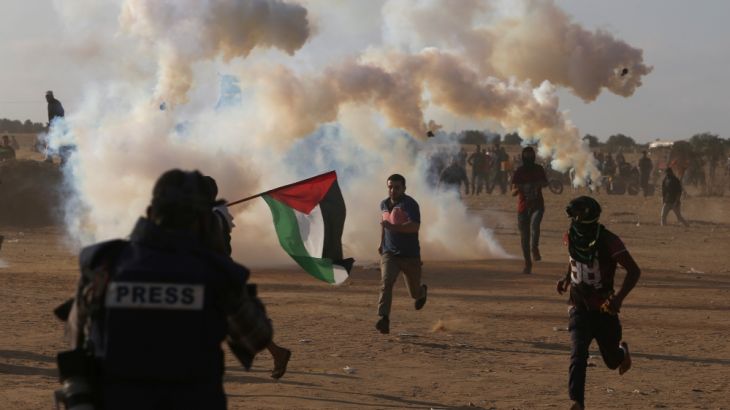 Palestinian demonstrators run from tear gas fired by Israeli troops during a protest marking the 70th anniversary of Nakba, at the Israel-Gaza border in the southern Gaza Strip