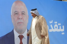A man walks past a campaign poster of Iraqi Prime Minister Haidar al-Abadi ahead of the parliamentary election, in Najaf