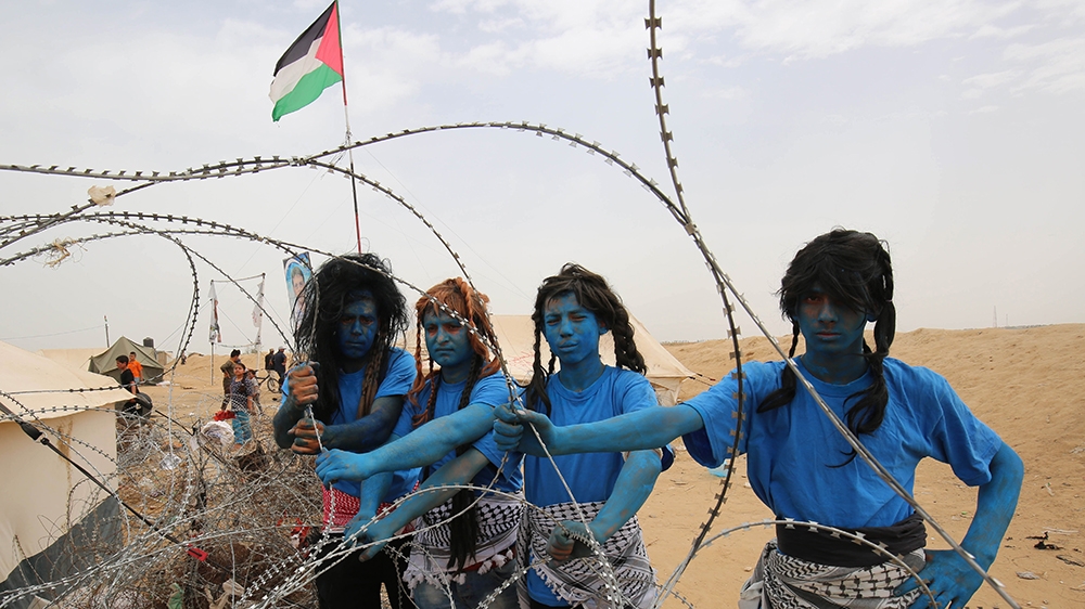 Palestinians with their faces painted like characters from the movie 'Avatar' pose for a picture at the Israel-Gaza border [Said Khatib/AFP]