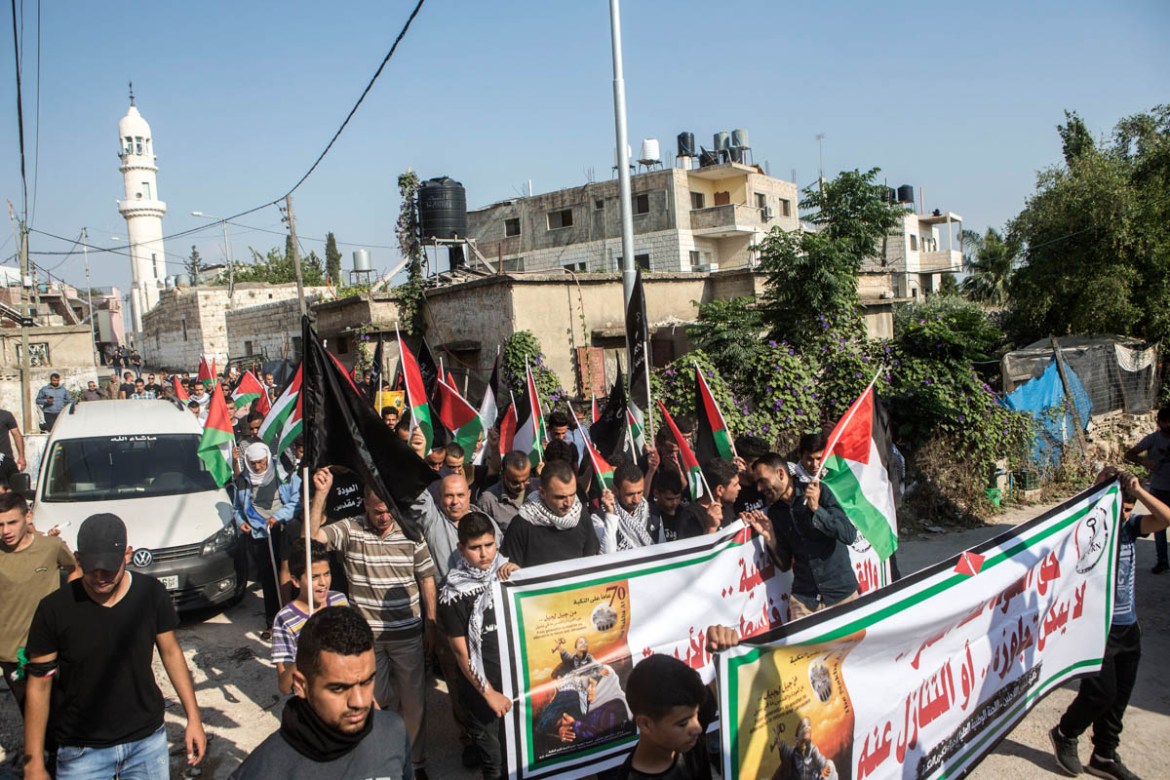 Palestinians march with banners, Palestinian and black flags during a demonstration for Nakba Day and in solidarity for Gaza, in the West bank village of Budrus.