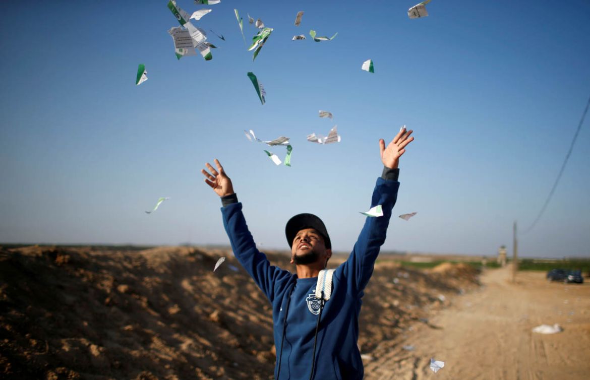 A Palestinian man throws leaflets dropped by the Israeli military during a protest against the U.S. embassy move to Jerusalem and ahead of the 70th anniversary of Nakba, at the Israel-Gaza border, eas