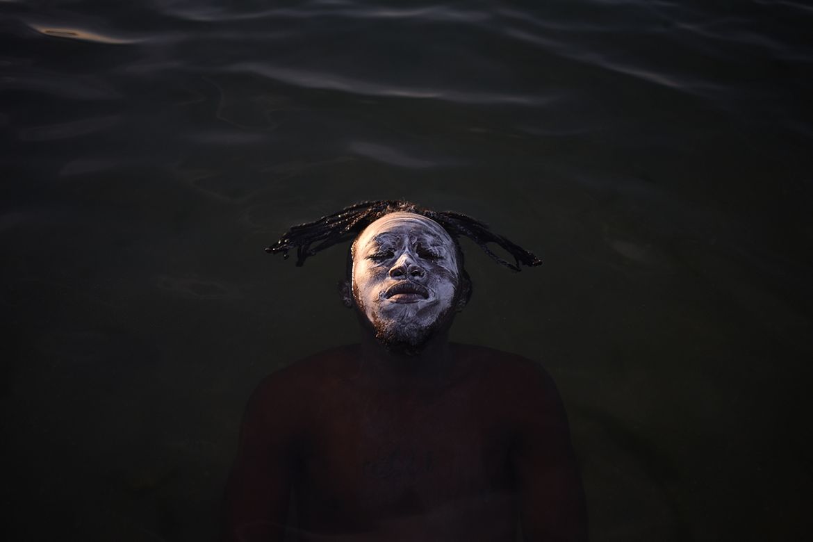 In a relaxed moment, Mbemba, a refugee from the Democratic Republic of Congo, is seen swimming in the Piscinão de Ramos, a vast man-made pool and beach adjacent to Guanabara Bay in Rio and part of Mar