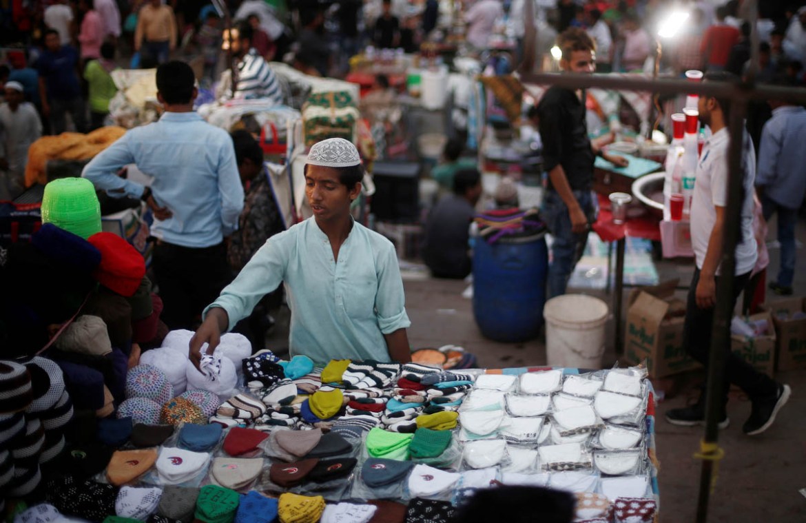 A boy looks at the skull caps before buying one on the eve of the holy fasting month of Ramadan, outside the Jama Masjid (Grand Mosque) in the old quarters of Delhi, India, May 16, 2018. REUTERS/Adnan