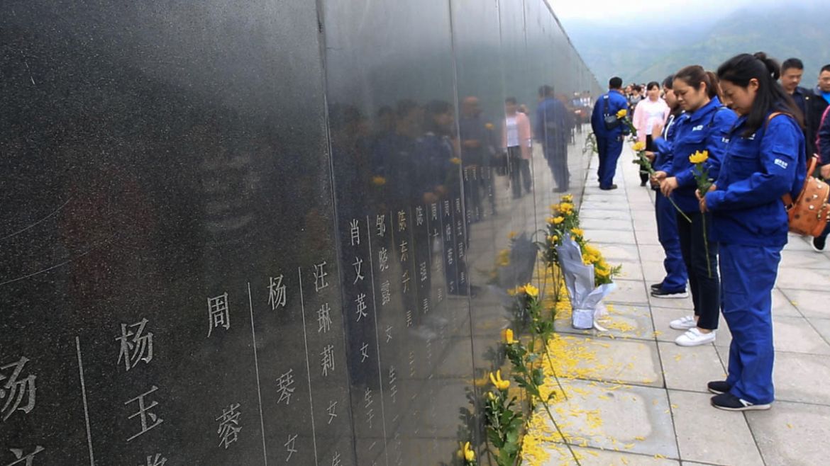 On this photo taken on May 10, 2018, workers from a power plant laying flowers to their colleagues who died in the earthquake in a mass tomb in Yingxiu where their names are on the wall. The mass tom