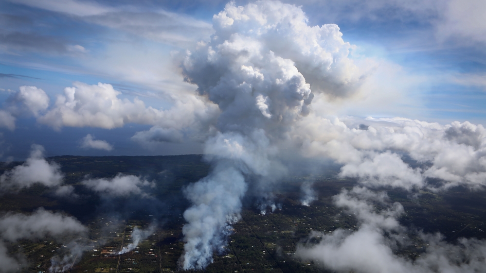 A plume of gas mixed with smoke from fires caused by lava rises, centre, amid clouds in the Leilani Estates neighborhood in the aftermath of eruptions from the Kilauea volcano on Hawaii's Big Island on May 6, 2018, in Pahoa, Hawaii [Mario Tama/Getty Images]