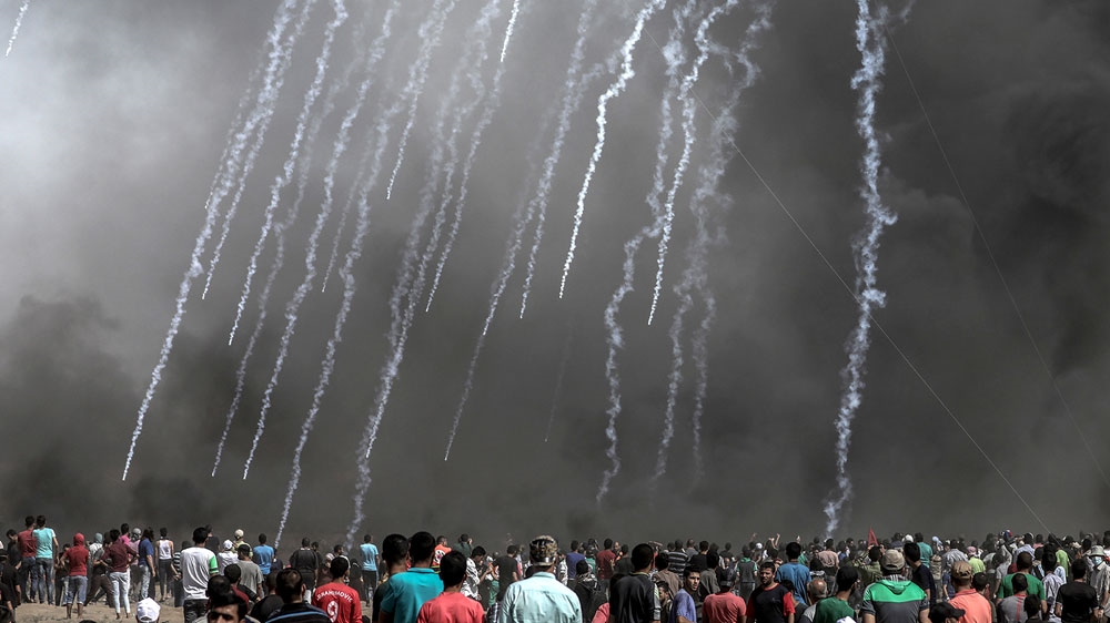 Israeli soldiers fire tear gas at Palestinians protesters in Gaza in June [EPA-EFE/Mohammed Saber]