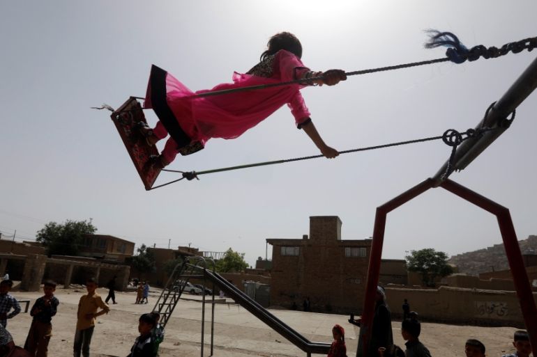 An Afghan child rides on a swing as others look on during the first day of the Muslim holiday of Eid al-Fitr, which marks the end of the holy month of Ramadan, in Kabul, Afghanistan