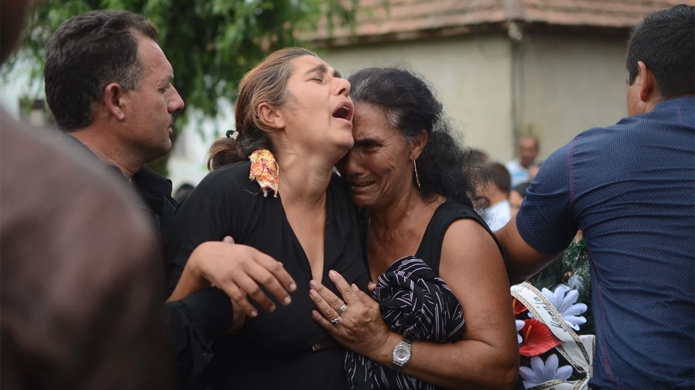 Women wail at the funeral of David Popp, who was killed in his sleep by suspected ultranationalists [Anya Denysenko/Al Jazeera]