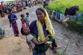 A Rohingya refugee woman who crossed the border from Myanmar a day before, carries her daughter and searches for help, in Palang Khali, Bangladesh October 17, 2017 [Reuters]