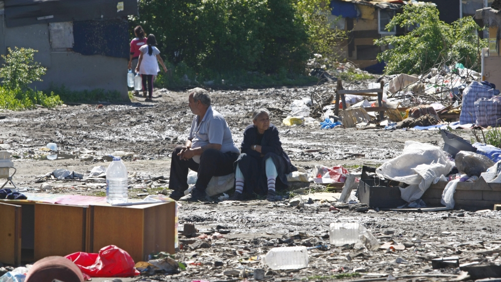 A Roma couple sit on the ground while they wait to be evacuated from a slum in Belgrade in 2012 [File: Ivan Milutinovic/Reuters]