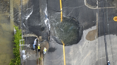 Water flows out from cracks in a road damaged by an earthquake in Takatsuki, Osaka Prefecture [Kyodo/Reuters]