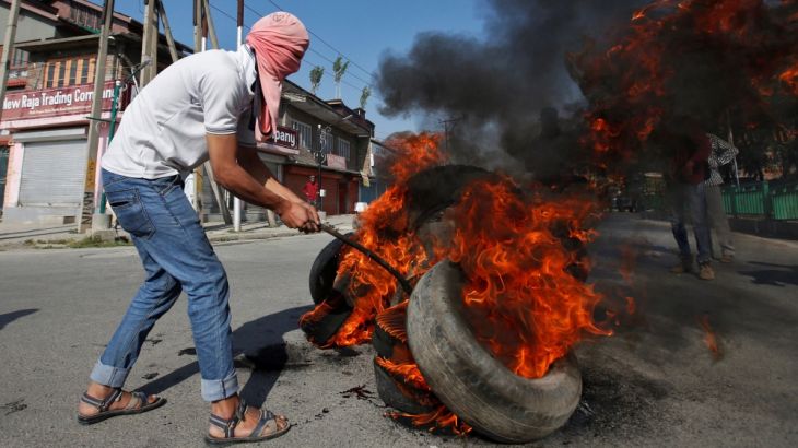Masked protester burns tires during the funeral of Kaisar Ahmad Bhat in Srinagar