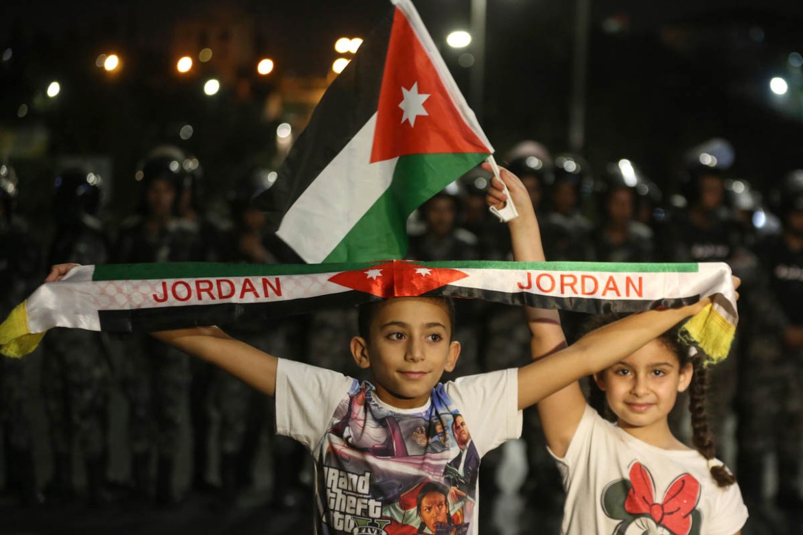 A girl and a boy hold a Jordanian flag and banner during a demonstration outside the Prime Minister''s office in Amman, early Tuesday, June 6, 2018. Jordan''s King Abdullah II on Tuesday appointed a new